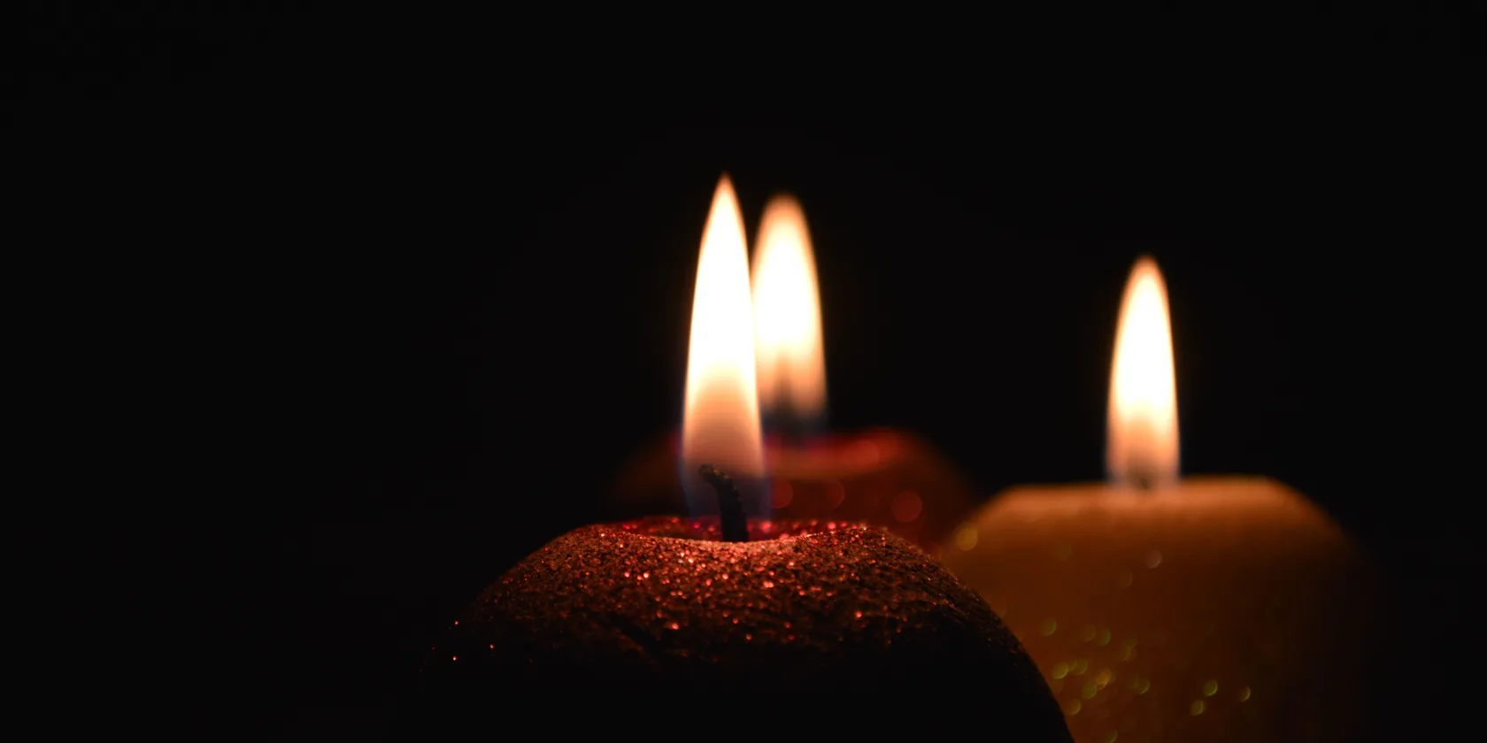 Flammes de bougies allumées dans la pénombre, ambiance chaude et apaisante